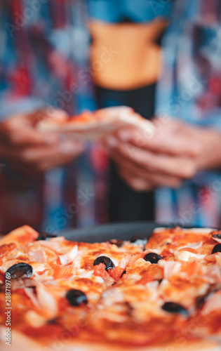 homemade style pizza with blurred man wearing plaid shirt as background