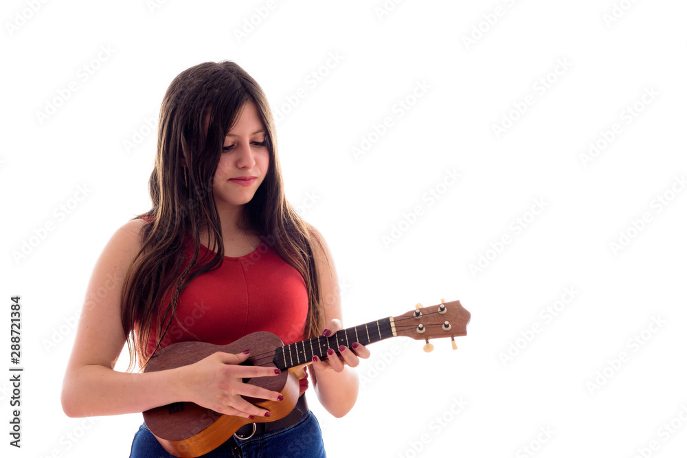 Teenage girl playing a ukelele, young artist with her musical instrument isolated Teenage girl playing a ukelele, young artist with her musical instrument isolated