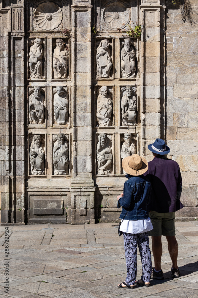 Tourists looking at ancient sculptures of Holy Door of Santiago de Compostela Cathedral