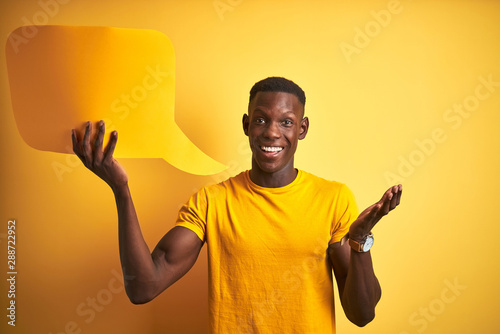 Young african american man holding speech bubble standing over isolated yellow background very happy and excited, winner expression celebrating victory screaming with big smile and raised hands
