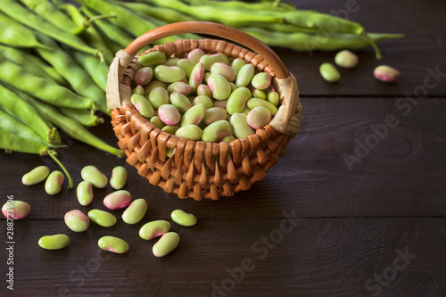 beans in a wicker basket. background with beans. beans and bean pods on a wooden background.