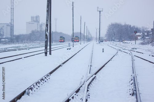 railway tracks go to the railway station where the locomotives stand in the winter on a snowy morning