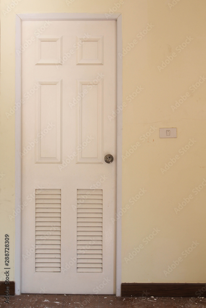 Fototapeta premium White wooden bathroom door with louver on concrete wall.