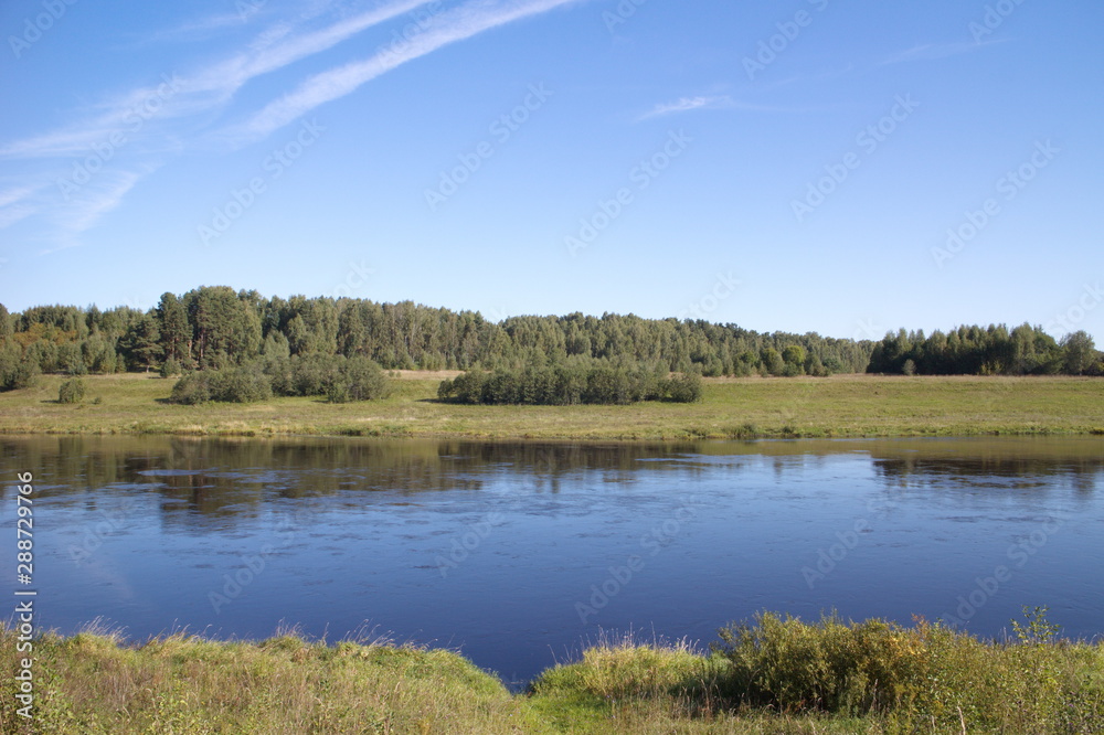 riverbank in the countryside blue sky traces of aircraft