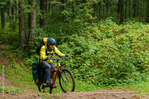 bikepacker crosses a ravine in a spruce forest photo