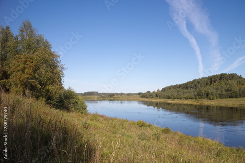 riverbank in the countryside blue sky traces of aircraft