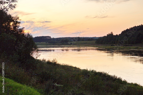 Sunset by the river in the summer countryside