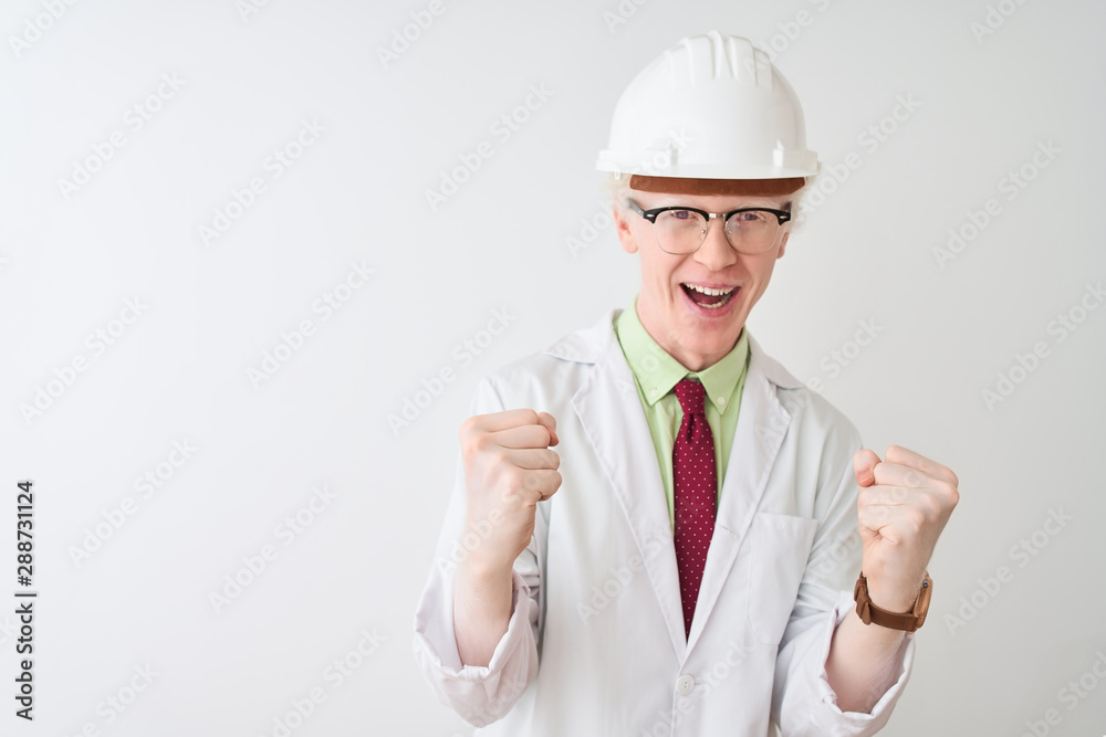 Albino scientist man wearing glasses and helmet standing over isolated white background celebrating surprised and amazed for success with arms raised and open eyes. Winner concept. Albino scientist man wearing glasses and helmet standing over isolated white background celebrating surprised and amazed for success with arms raised and open eyes. Winner concept.