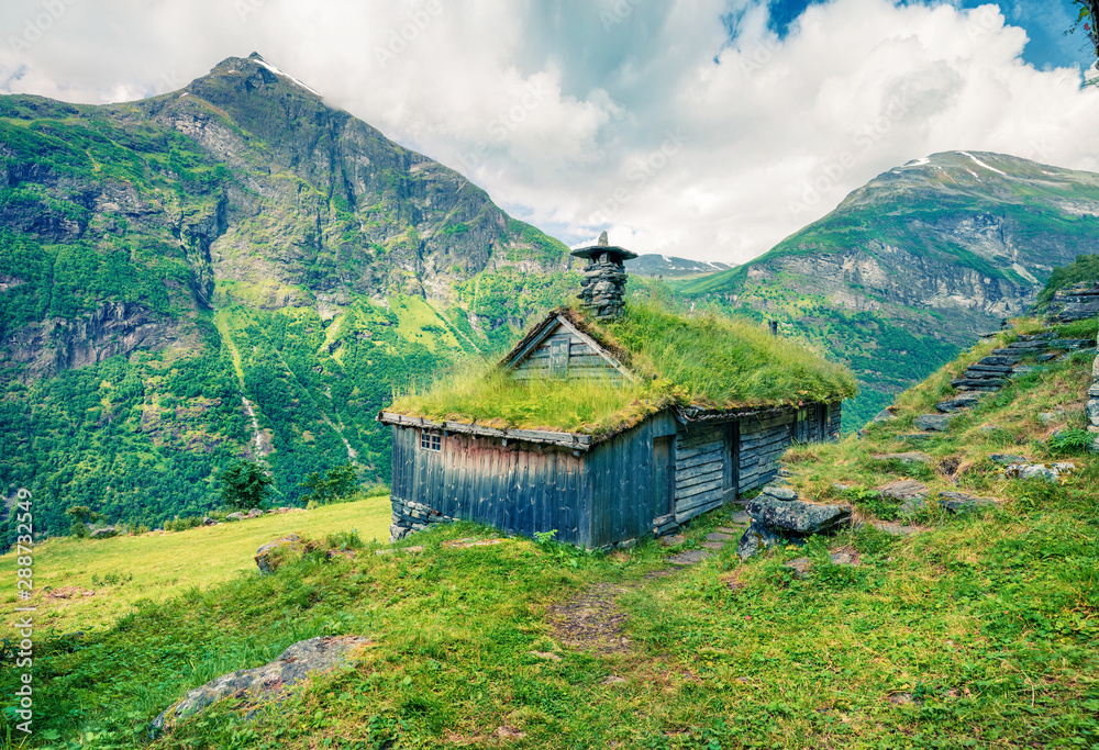 Norwegian typical grass roof wooden old house near Seven Sister waterfall. Colorful summer morning in Norway, Europe. Beauty of countryside concept background. Instagram filter toned.