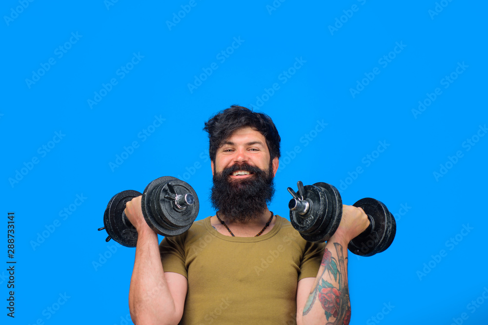 Fitness man with dumbbells. Strong handsome sportsman making weightlifting. Bearded man with dumbbells during an exercise. Man raising dumbbells. Muscular fitness man working out with dumbbells.
