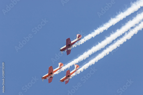 Three colorful jets flying in the sky and performing a show - smoke coming up from the planes