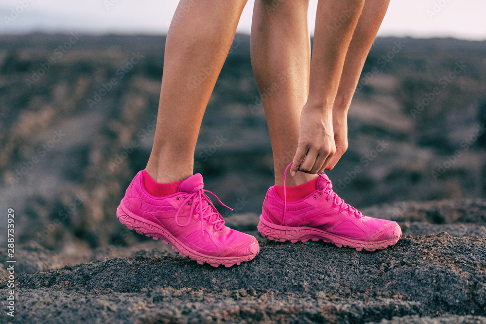 Fit run girl getting ready to walk on mountain rocsk tying up laces of  trail running shoes - hot pink fashion footwear runner activewear  lifestyle. Stock Photo | Adobe Stock