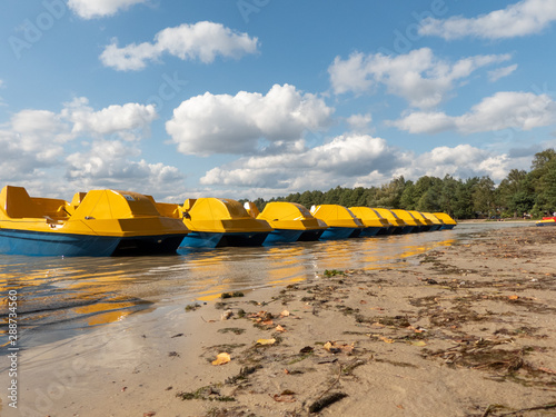 Resort on the beach after the tourist season abandoned yellow pedalo lined up in a row