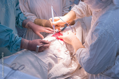 Doctors - pediatric surgeons, in a sterile operating room, perform kidney surgery