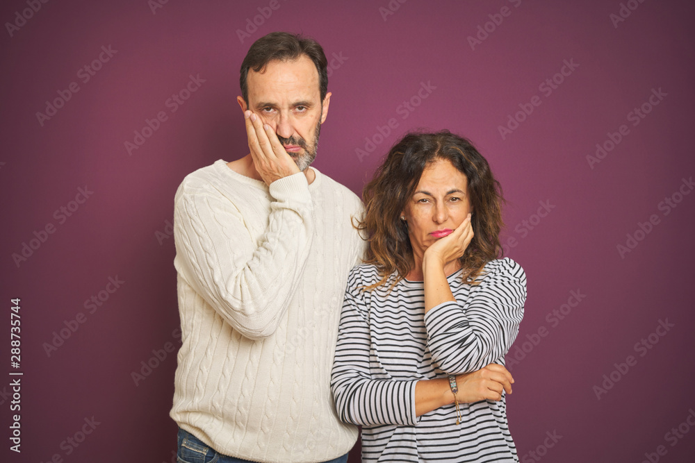 Naklejka premium Beautiful middle age couple wearing winter sweater over isolated purple background thinking looking tired and bored with depression problems with crossed arms.