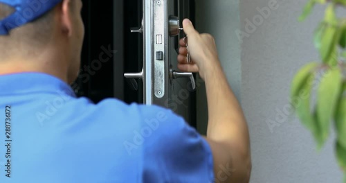 locksmith in blue uniform installing new house door lock photo