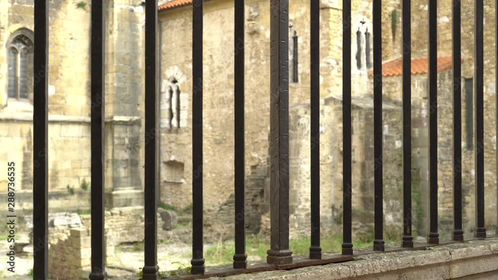 The lock on the ancient rusty metal gate. Behind the fence are the ruins of an old building