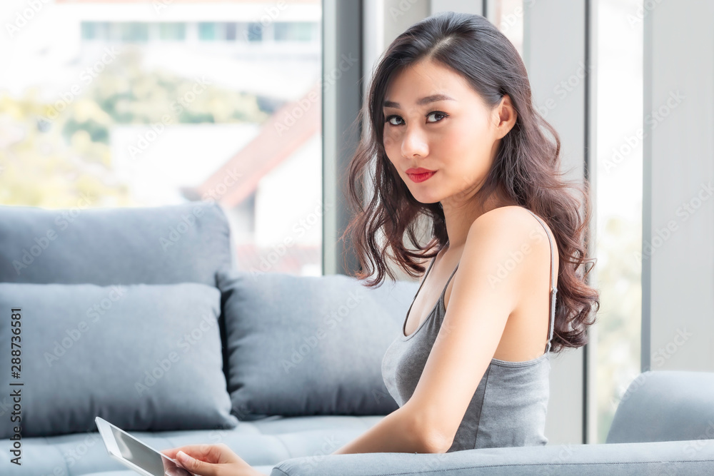Beautiful woman sitting and shopping online with tablet in living room. Beautiful woman sitting and shopping online with tablet in living room.