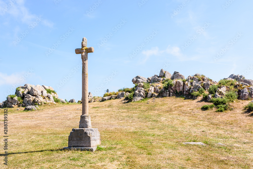 Eroded granite calvary of the chapel of Saint-Nicolas in Bugueles, Brittany, France, in front of a granite outcrop under a bright sunshine. Eroded granite calvary of the chapel of Saint-Nicolas in Bugueles, Brittany, France, in front of a granite outcrop under a bright sunshine.