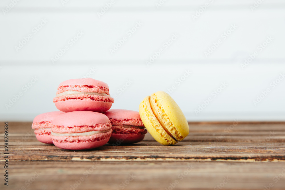Sweet colorful French macaroon cookies dessert on brown wooden table over white wooden background Sweet colorful French macaroon cookies dessert on brown wooden table over white wooden background