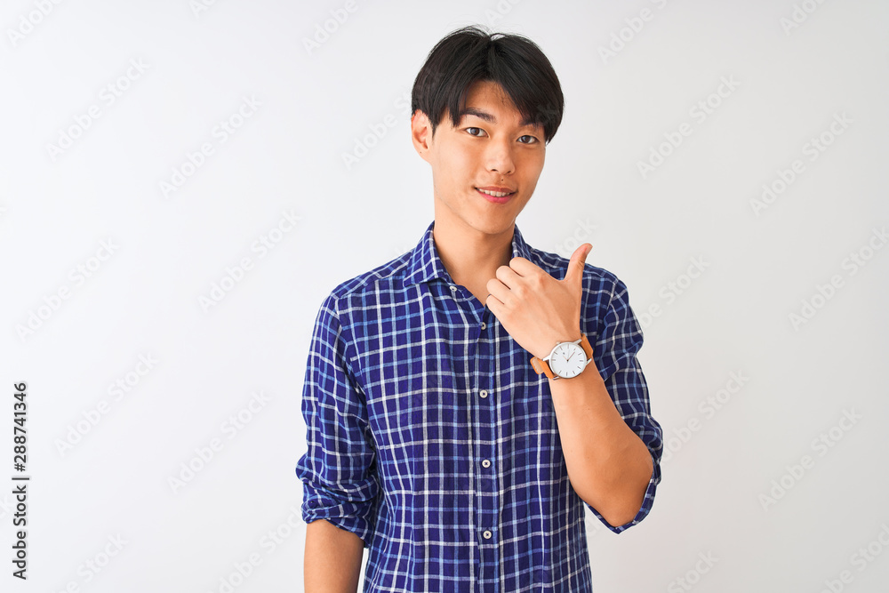 Young chinese man wearing casual blue shirt standing over isolated white background doing happy thumbs up gesture with hand. Approving expression looking at the camera showing success. Young chinese man wearing casual blue shirt standing over isolated white background doing happy thumbs up gesture with hand. Approving expression looking at the camera showing success.
