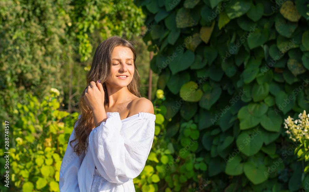 Young beautiful woman with bare shoulders in white clothes in the garden Young beautiful woman with bare shoulders in white clothes in the garden