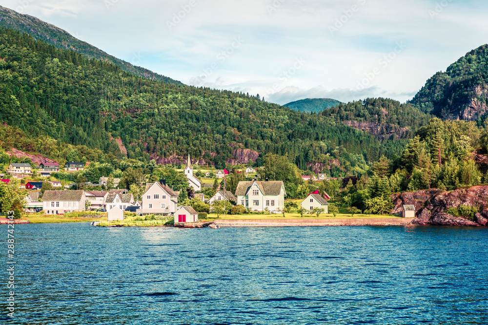 Sunny summer view of typical Norwegian village on the shore of fjord. Beautiful morning scene of Norway, Europe. Traveling concept background. Instagram filter toned.