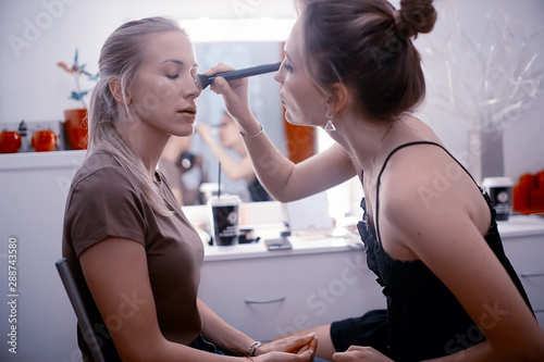 professional make-up in the beauty salon / master makes a professional fresh summer make-up of a beautiful model in the salon
