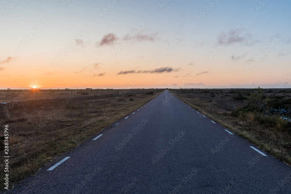 Straight road by sunrise in a great barren landscape