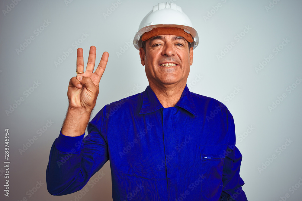 Handsome middle age worker man wearing uniform and helmet over isolated white background showing and pointing up with fingers number three while smiling confident and happy.