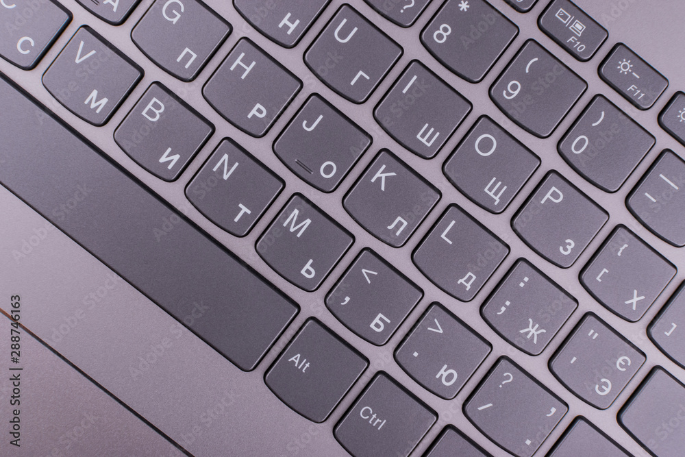 A silver-gray laptop with a modern keyboard connected to the Internet and a computer network lies on an orange desktop in an office A silver-gray laptop with a modern keyboard connected to the Internet and a computer network lies on an orange desktop in an office