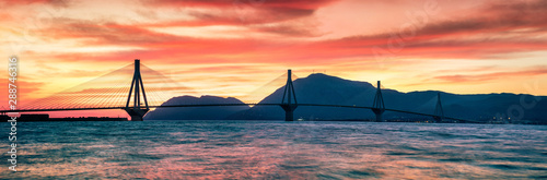 Impressive evening sunset with Rion-Antirion Bridge. Colorful spring panorama of the Gulf of Corinth, Greece, Europe. Beauty of countryside concept background. Artistic style post processed photo.
