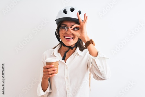 Fotografía Beautiful businesswoman wearing bike helmet drinking coffee over isolated white