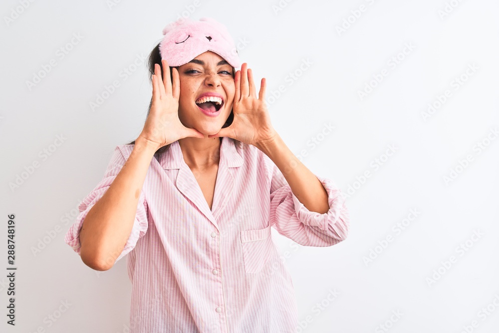 Young beautiful woman wearing sleep mask and pajama over isolated white background Smiling cheerful playing peek a boo with hands showing face. Surprised and exited Young beautiful woman wearing sleep mask and pajama over isolated white background Smiling cheerful playing peek a boo with hands showing face. Surprised and exited