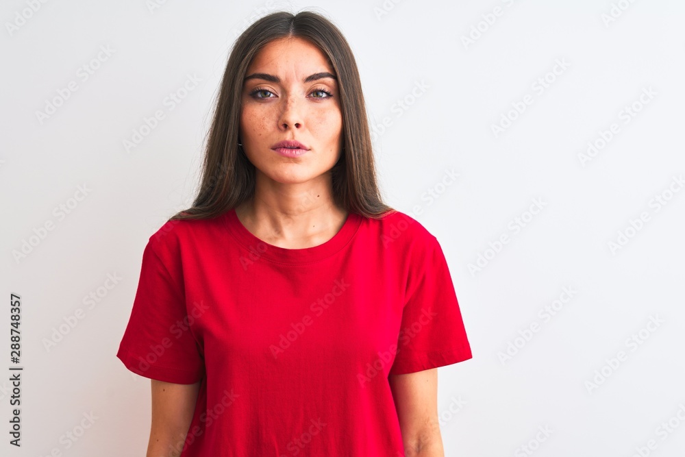 Young beautiful woman wearing red casual t-shirt standing over isolated white background with serious expression on face. Simple and natural looking at the camera. Young beautiful woman wearing red casual t-shirt standing over isolated white background with serious expression on face. Simple and natural looking at the camera.