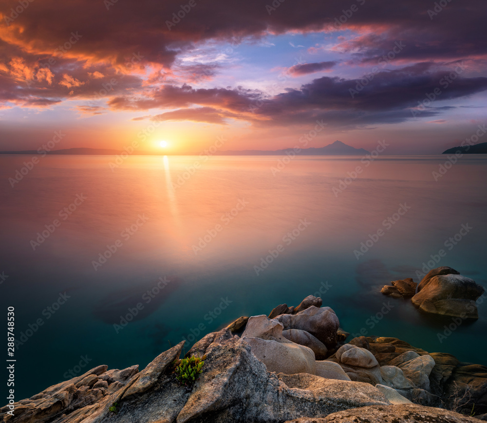 Amazing landscape of sunrise at sea.  Colorful morning view of dramatic sky, seascape and rock. Long exposure image. Greece. Mediterranean Sea. Concept of nature background.