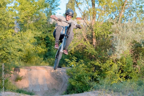 Foto young guy cyclist does jumps and tricks on a bike