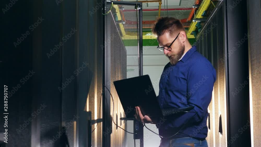 Computer engineer is connecting his laptop to the server Computer engineer is connecting his laptop to the server