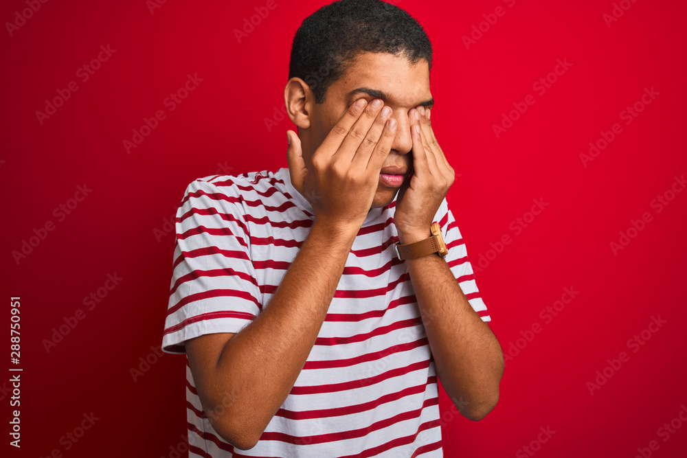 Young handsome arab man wearing striped t-shirt over isolated red background rubbing eyes for fatigue and headache, sleepy and tired expression. Vision problem Young handsome arab man wearing striped t-shirt over isolated red background rubbing eyes for fatigue and headache, sleepy and tired expression. Vision problem