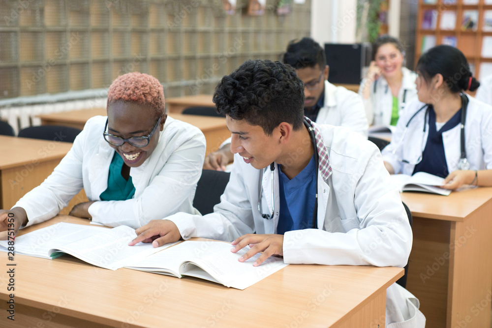 A group of young multinational races, medical students. They write the exam while sitting at the table.
