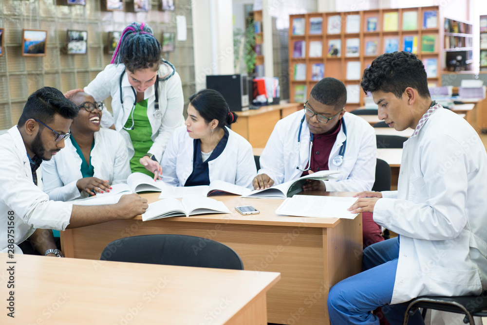 young doctors A group of people of mixed race, sitting at the table, talking, discussing health problems. young doctors A group of people of mixed race, sitting at the table, talking, discussing health problems.