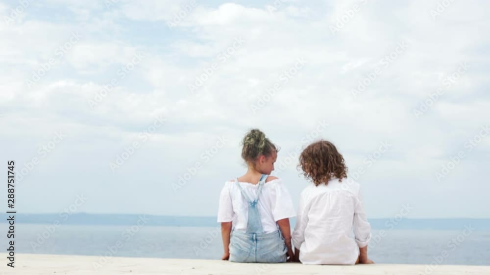 Loving boy and girl sitting on the seashore hugging. Valentines Day, summer vacation, teenagers first love Loving boy and girl sitting on the seashore hugging. Valentines Day, summer vacation, teenagers first love