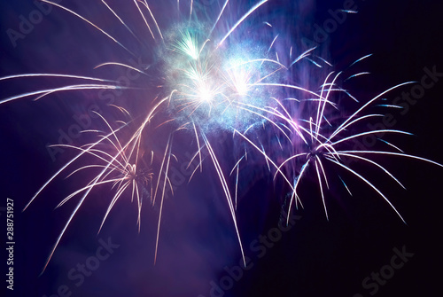 Blue colorful fireworks on black night sky background. Holiday celebration
