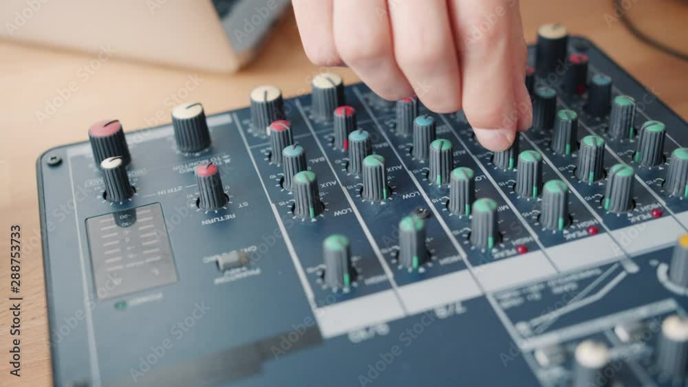 Close-up shot of male hand adjusting sound using modern audio equipment on table in recording studio. Contemporary technology, people and electronics concept. Close-up shot of male hand adjusting sound using modern audio equipment on table in recording studio. Contemporary technology, people and electronics concept.