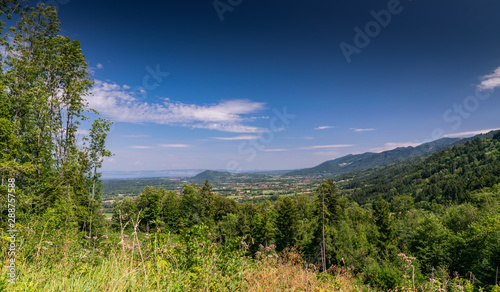  City landscape in the mountains, hills, fields, forests, green meadows, lakes in the distance and blue sky with clouds,focus area in the city.Haute-Savoie in France.