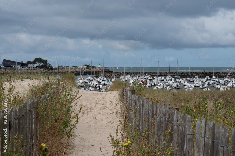 Path through the dunes to reach the seaside with boats Path through the dunes to reach the seaside with boats