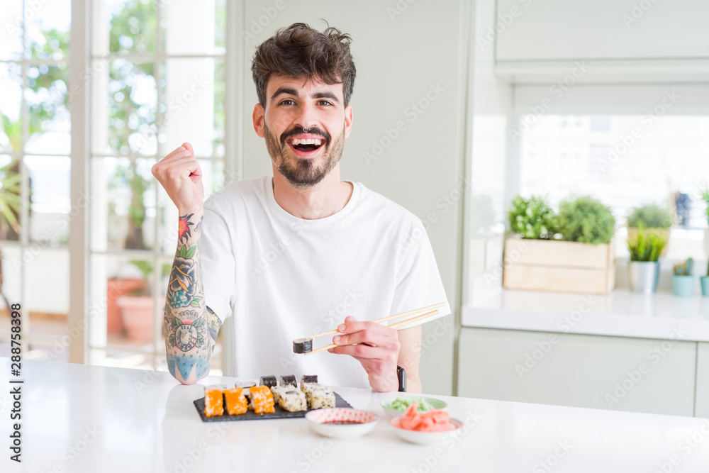 Young man eating asian sushi from home delivery screaming proud and celebrating victory and success very excited, cheering emotion Young man eating asian sushi from home delivery screaming proud and celebrating victory and success very excited, cheering emotion
