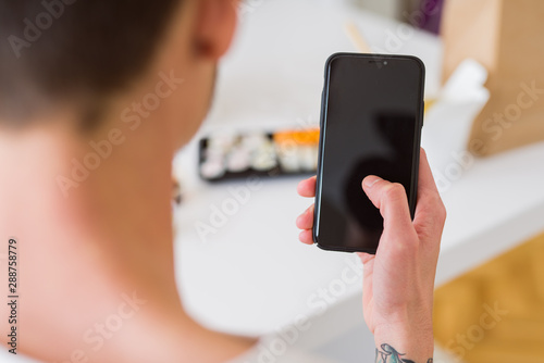 Close upf man using smartphone to orden take away asian food from delivery photo