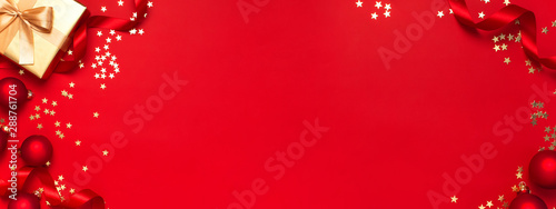 New Year Christmas golden presents with ribbon, Christmas balls, gold confetti stars on red background top view. Flat lay Xmas holiday 2020 celebration. Gift boxes greeting card Festive decorations