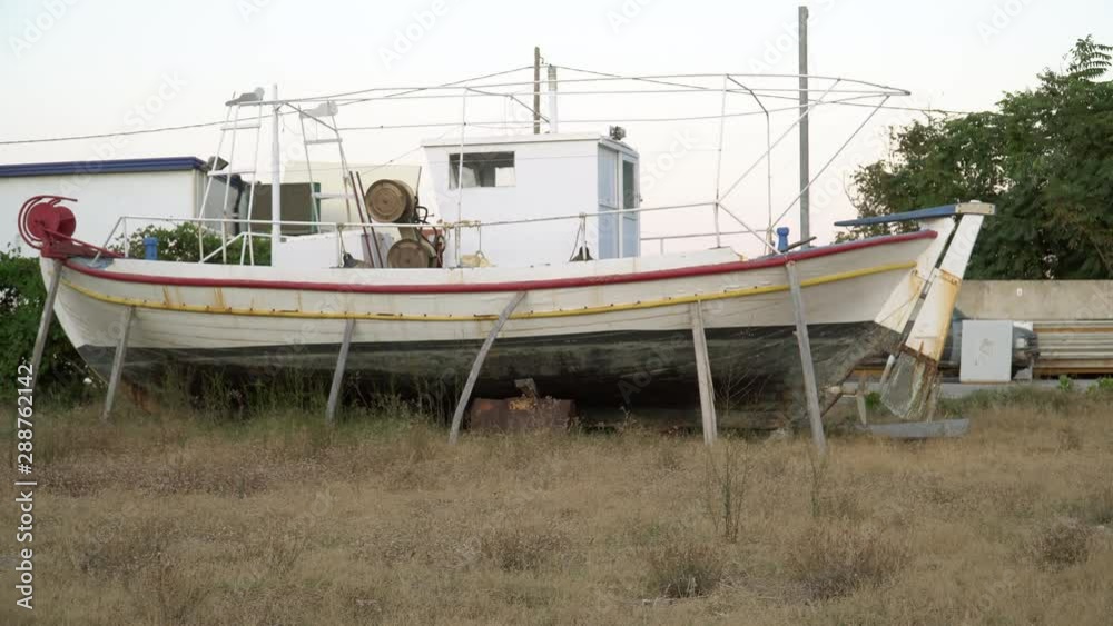 Retired used boat on the land. Old fishing boat on the meadow supported with wooden sticks. Retired used boat on the land. Old fishing boat on the meadow supported with wooden sticks.